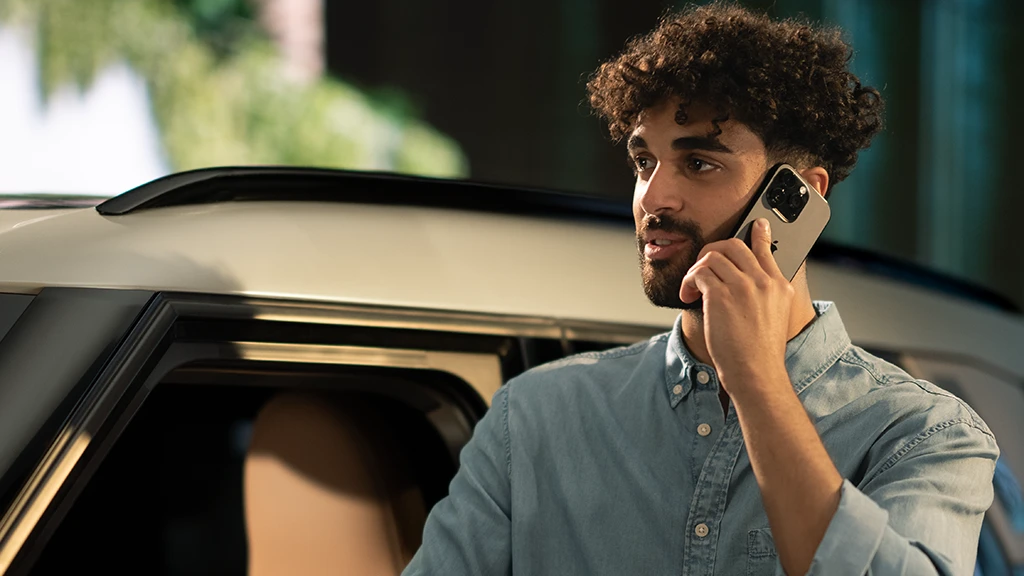 Человек стоит рядом с автомобилем MINI и разговаривает по смартфону.